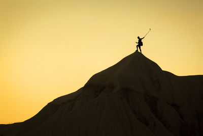 Low angle view of silhouette man standing on mountain against clear sky
