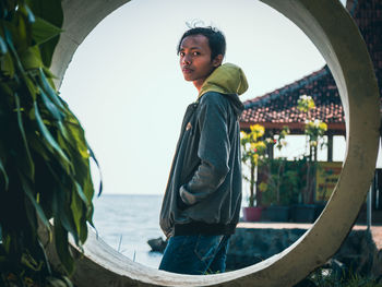 A stylish man in the center of a circle on a house and sea background