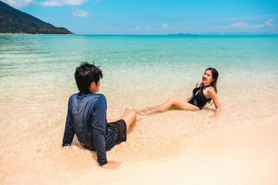 Friends enjoying at beach against sky