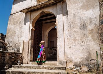 Rear view of woman walking in front of historical building