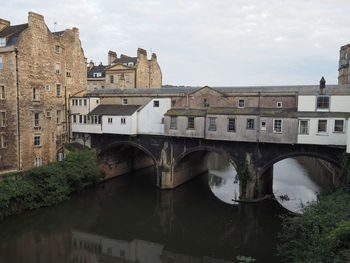 Arch bridge over river against buildings in city