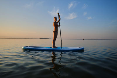 Full length of woman paddleboarding in sea