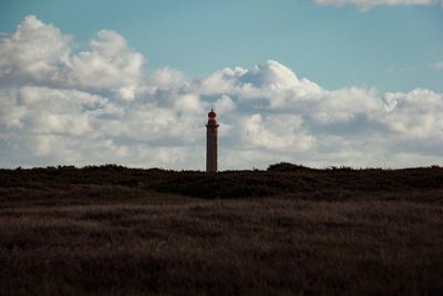 Lighthouse on field against sky