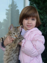 The little cute girl holds the kitten tenderly in her arms 