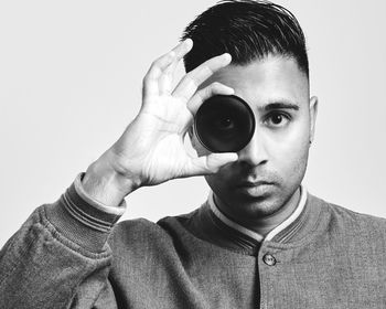 Portrait of young man photographing against white background