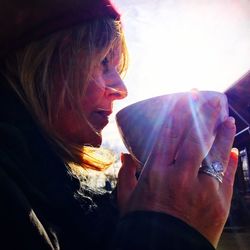 Close-up of woman drinking soup in bowl against sky