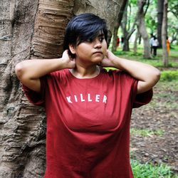 Young woman standing against tree