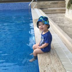 Portrait of boy sitting at swimming pool