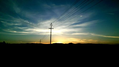 Scenic view of electricity pylon at sunset