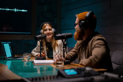 Joyful young stylish radio show hosts record fresh podcast episode in loft studio