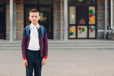 Portrait of boy standing on footpath