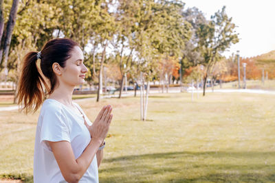 Young woman in the park relaxing, meditating, doing yoga.