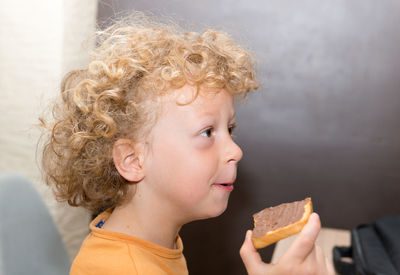 Boy looking away while holding bread with peanut butter