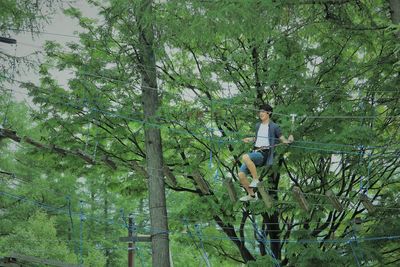 Boy zip lining against trees in forest