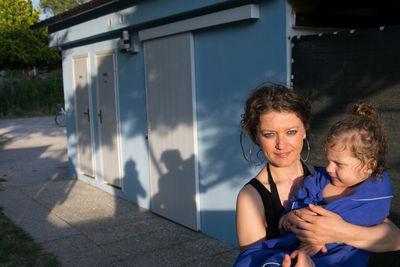 Portrait of smiling mother holding daughter on footpath 