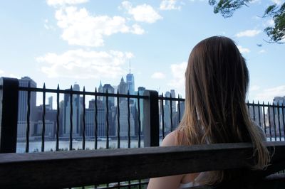 Rear view of woman standing by railing against sky