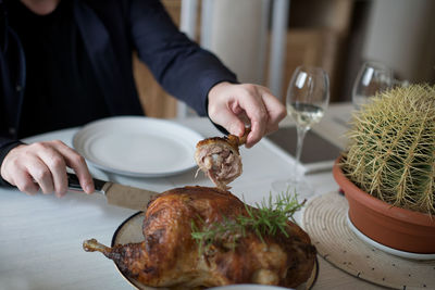 Midsection of mature man eating meat on dining table