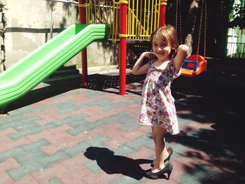 Full length of smiling girl wearing high heels while standing at playground