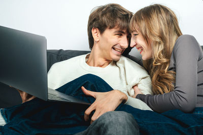 Young woman using laptop while sitting on sofa at home