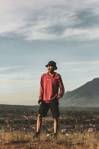 Full length of young man standing on land against sky