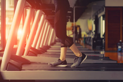 Low section of woman exercising on treadmill in gym