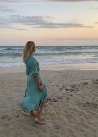 Full length of woman on beach against sky during sunset