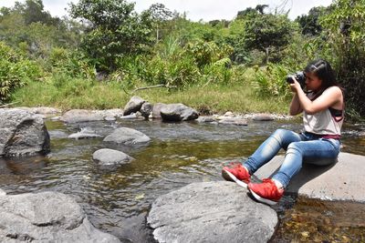 Side view of woman sitting on rock