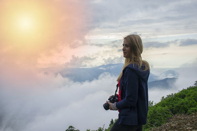 Rear view of woman standing against sky during sunset