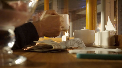 Close-up of hand holding coffee cup on table