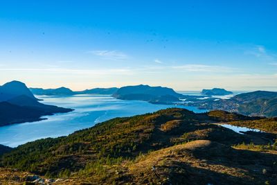 Scenic view of sea and mountains against blue sky