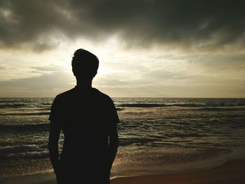 Rear view of silhouette man standing at beach