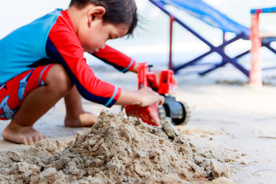 Side view of boy playing with toy at sandy beach