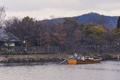 People on riverbank against sky