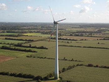 Wind turbines on field against sky