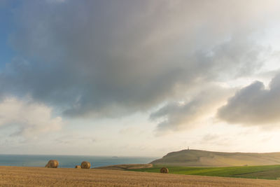 Hay bales on field against sky