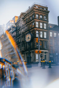 Clock tower amidst buildings in city against sky