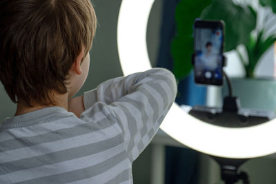 Rear view of boy holding camera