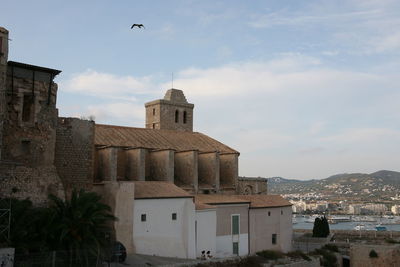 View of buildings in city against cloudy sky