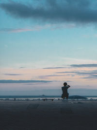 Silhouette man standing on beach against sky during sunset