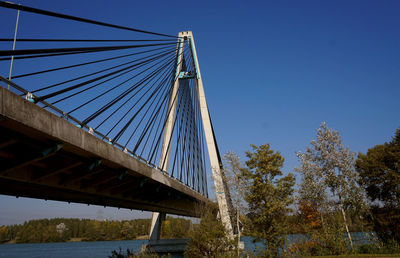 Low angle view of bridge over river against clear blue sky