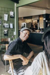 Happy male owner talking with female coworker while sitting at cafe