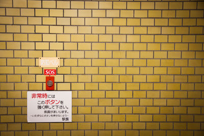 Close-up of road sign against brick wall