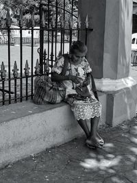 Full length of woman sitting against building