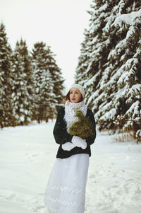 Redhead beautiful woman in green sweater and white gloves walking in the frozen winter forest.