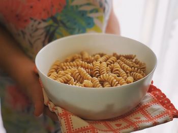 Midsection of woman holding bowl with pastas