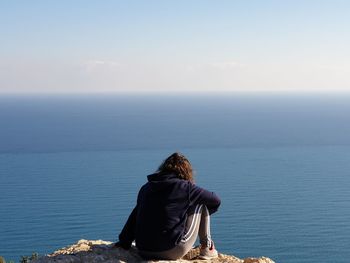 Rear view of man looking at sea against sky