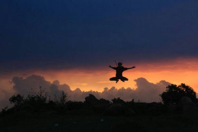 Silhouette of person jumping against sky at sunset