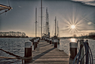 Sailboats on pier by sea against sky