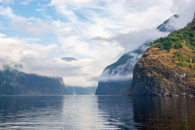 Scenic view of sea by mountain against sky