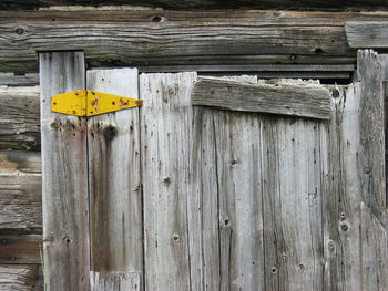 Close-up of yellow hinge on old wooden door